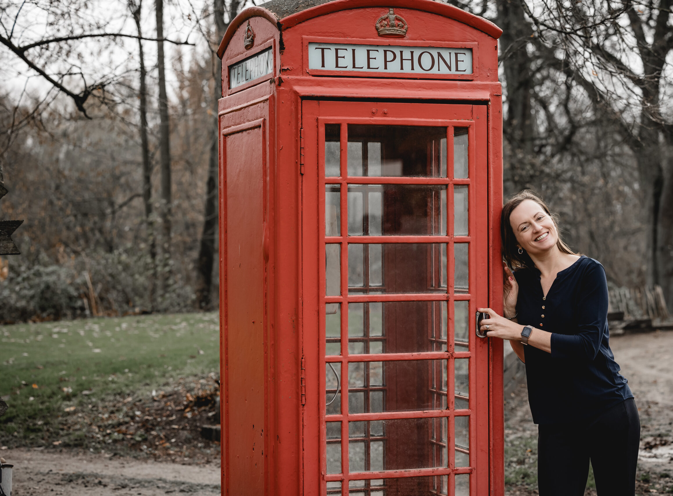 Britta Sojka lehnt lachend an einer roten britischen Telefonzelle